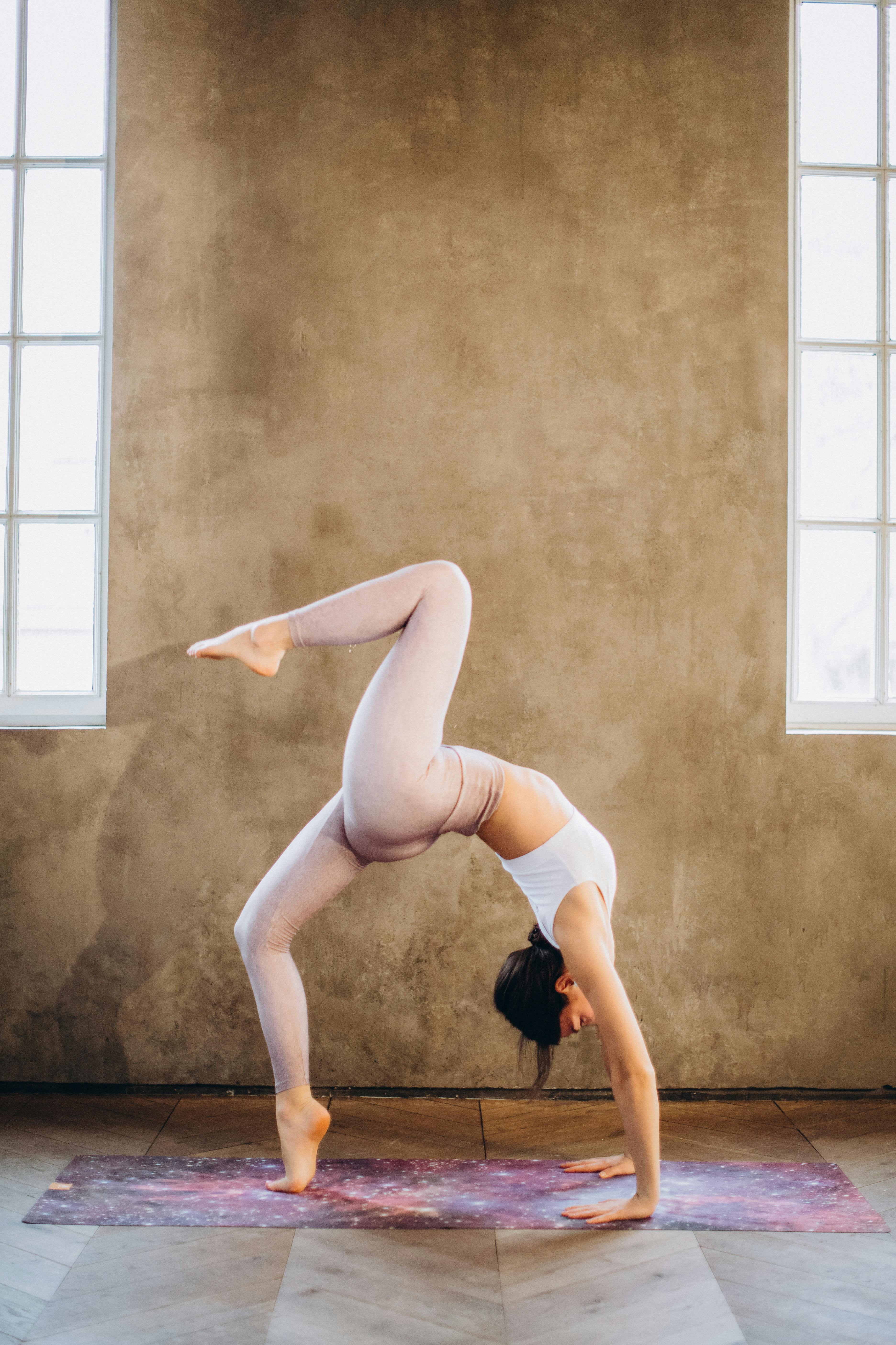 Person performing a yoga pose on a mat against a textured wall.